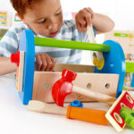 Little boy concentrating while playing with kid toolbox, turning a wrench.