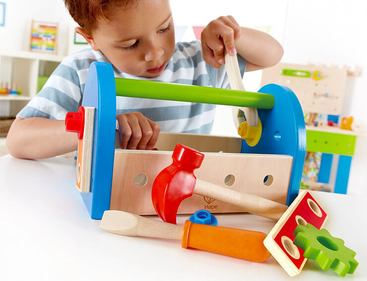 Little boy concentrating while playing with kid toolbox, turning a wrench.